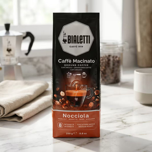 Bolsa de café molido Bialetti con avellanas (250 g) con taza e ilustración de avellanas.
