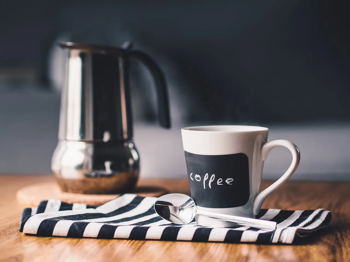 Cafetera italiana Bialetti Kitty de acero blanca con asa negra, lista para servir
