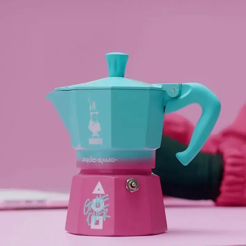 Cafetera italiana moka turquesa con base magenta, tapa con chimenea y asa