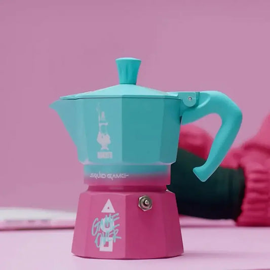 Cafetera italiana moka turquesa con base magenta, tapa con chimenea y asa