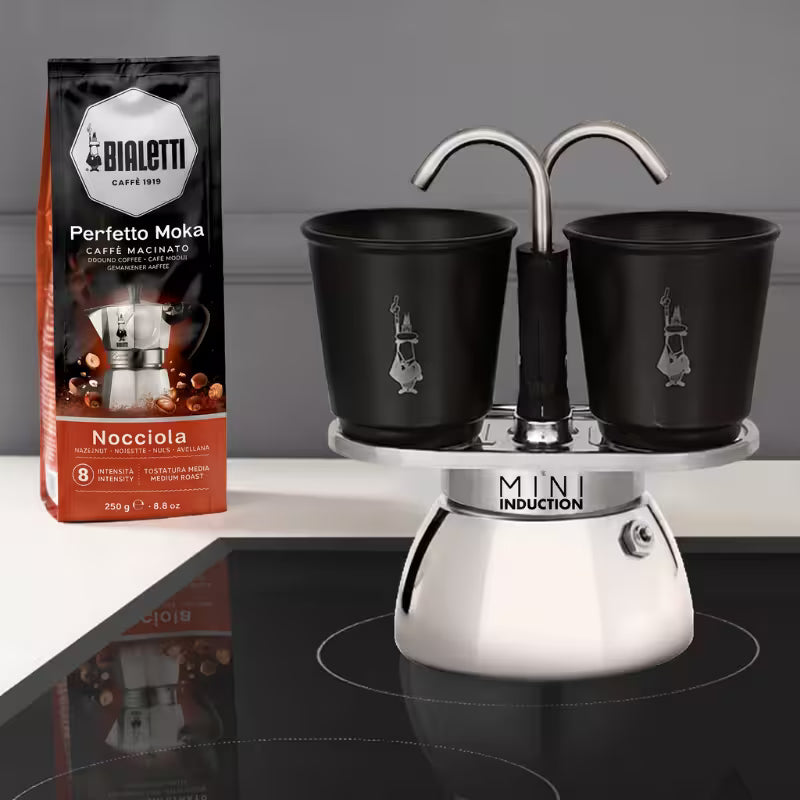 Cafetera Mini Induction con dos tazas negras sobre base metálica