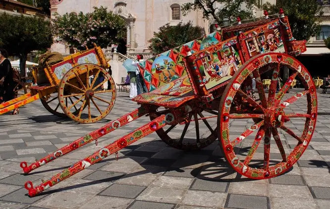 Carro decorativo multicolor con detalle tipo patrón, ruedas grandes y estructura roja