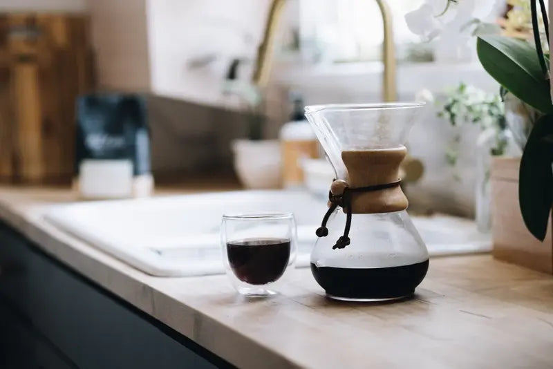 Cafetera Chemex de vidrio con café en preparación y filtro de papel