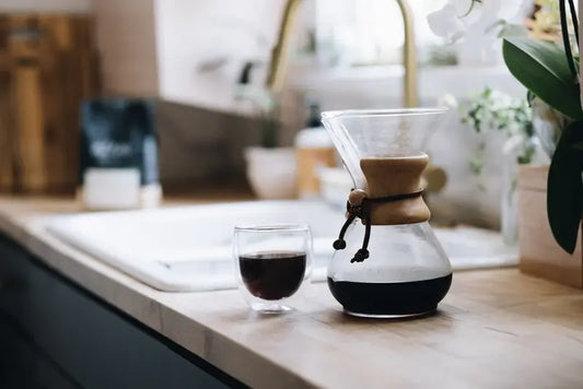 Cafetera Chemex de vidrio con café en preparación y filtro de papel