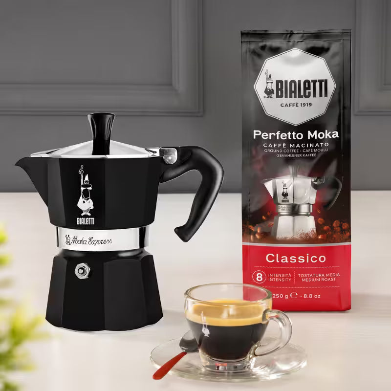 Cafetera moka italiana Bialetti negra con asa y taza de café