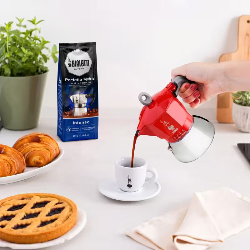 Cafetera italiana moka Bialetti roja vertiendo café a una taza blanca