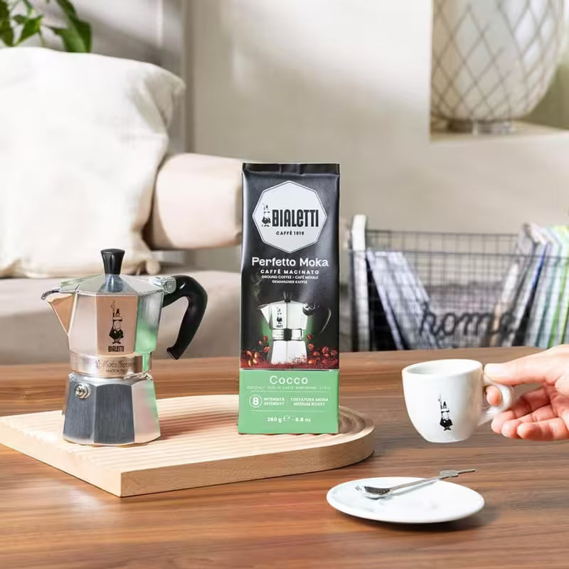Bolsa de café molido Bialetti Perfetto Moka Coco, junto a una taza