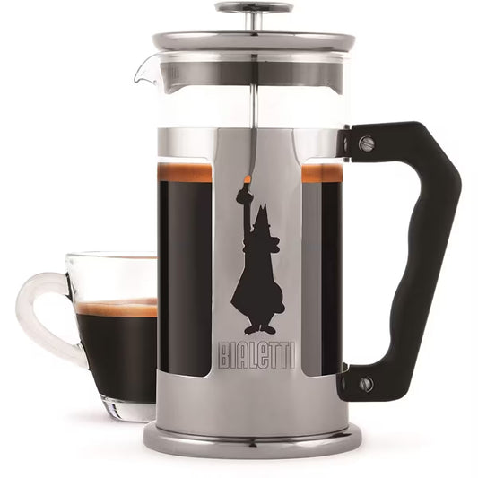 Prensa francesa Bialetti de acero inoxidable con asa negra y jarra de vidrio con café al fondo